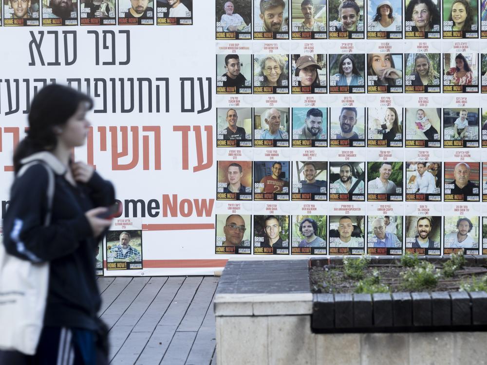 A woman in Kfar Saba, Israel, passes a wall on Monday covered with photos of hostages kidnapped to the Gaza Strip during the Oct. 7, 2023, Hamas-led attack.