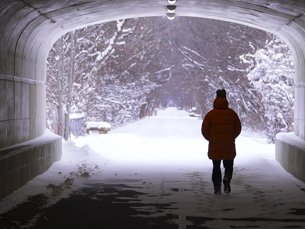 A pedestrian makes their way though a tunnel along the snow-covered Monon Trail in Carmel, Ind.