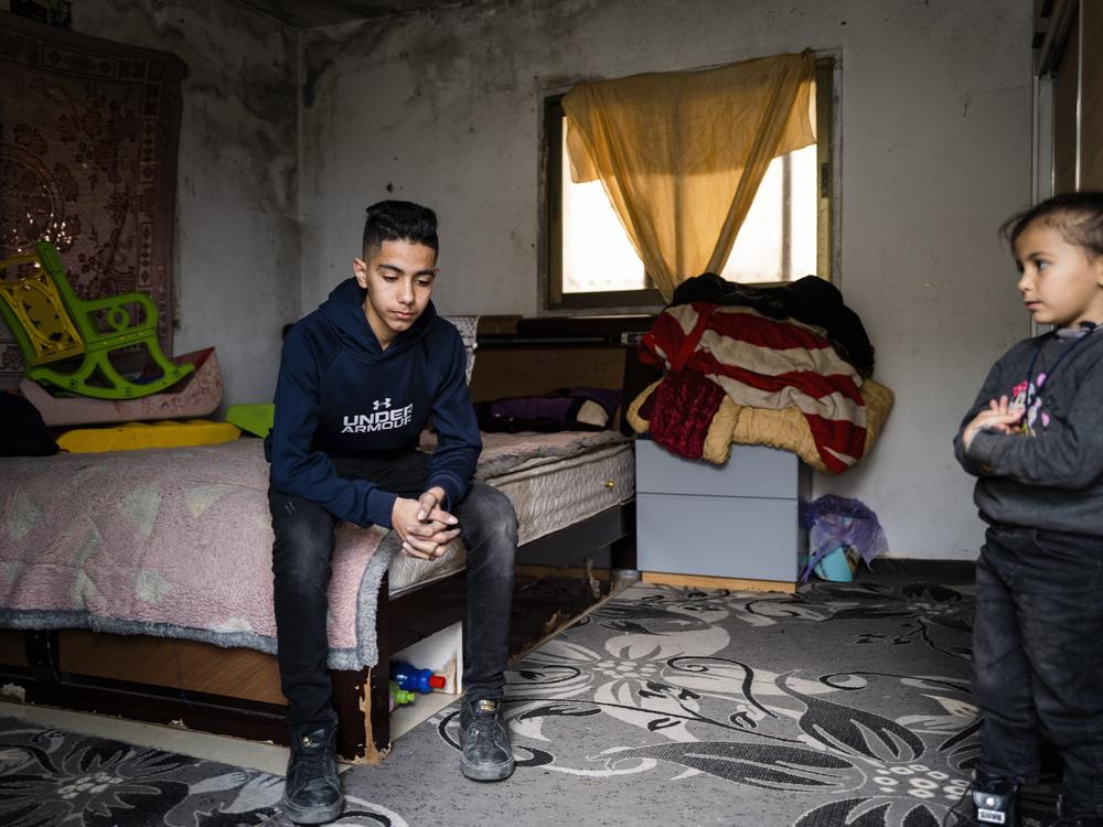 Noor Assi, 15, sits on his bed while watched by his 5-year-old sister Jenna in the village of Qarawat Bani Hassan, Israeli-occupied West Bank, on Feb. 23.