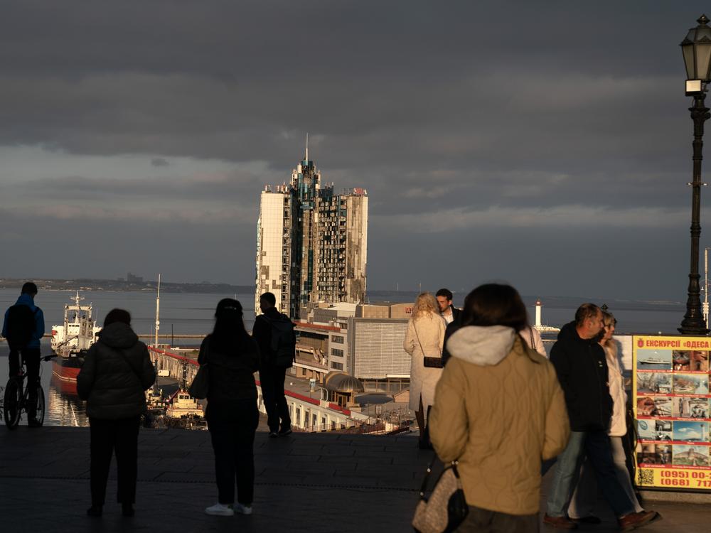 People gather at the top of the Potemkin Stairs at sunset in Odesa, Ukraine, on Oct. 27, 2024. A hotel, destroyed by Russian missiles, can be seen in the background.