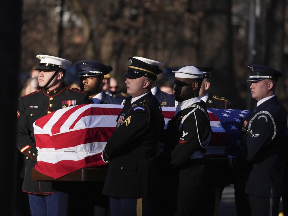 A military body bearer team carries the casket of former President Jimmy Carter into the Jimmy Carter Presidential Library and Museum to lie in repose in Atlanta, Ga.