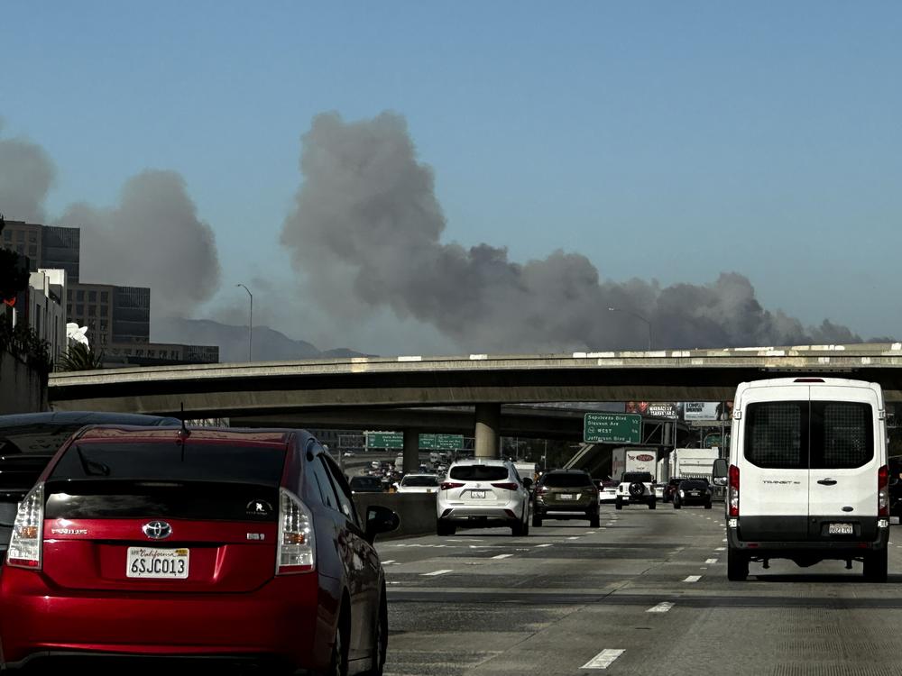 Smoke from a brush fire in the Pacific Palisades rises over the 405 freeway in Los Angeles on Tuesday.