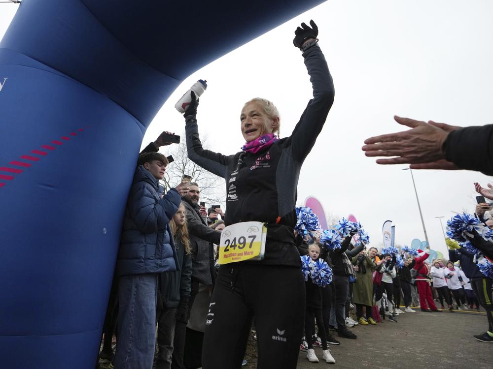 Belgian ultra runner Hilde Dosogne, center, is cheered on as she crosses the finish line during her 366th consecutive marathon in Ghent, Belgium, on Dec. 31, 2024.