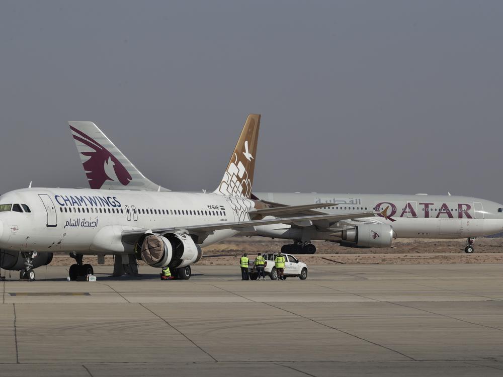 Qatar Airways plane, background, a first international commercial flight since the fall of former Syrian President Bashar al-Assad, lands at Damascus international airport arriving from Qatar, in Damascus, Syria on Tuesday.