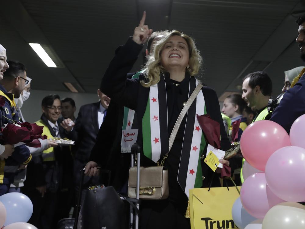 A Syrian woman who arrived at a first international commercial flight since the fall of former Syrian President Bashar Assad shouts anti-Assad slogans at the arrival terminal of Damascus international airport, in Damascus, Syria on Tuesday.