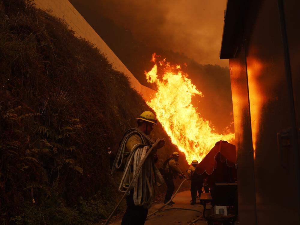 Firefighters protect structures from the advancing Palisades Fire in the Pacific Palisades neighborhood of Los Angeles.
