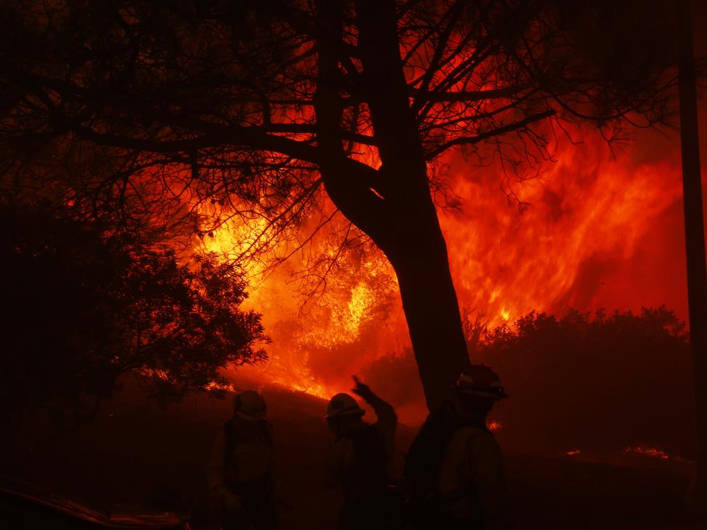 Firefighters stage in front of the advancing Palisades Fire in the Pacific Palisades neighborhood of Los Angeles.