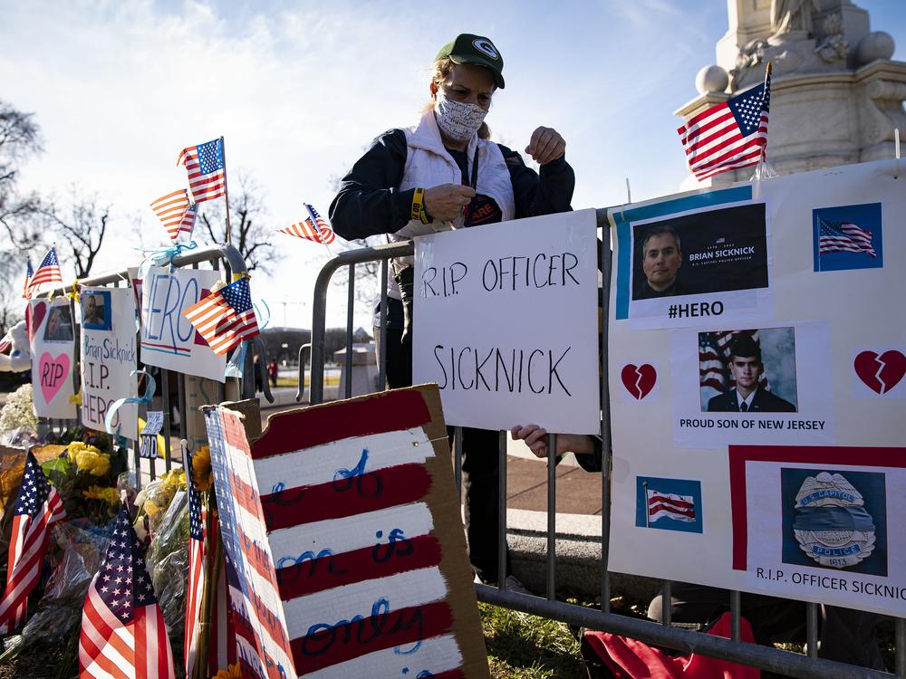 Anne Seymour adds a sign at a memorial for U.S. Capitol Police Officer Brian Sicknick, who collapsed and died following the Jan. 6 attack, near the Capitol on January 10, 2021 in Washington, D.C.