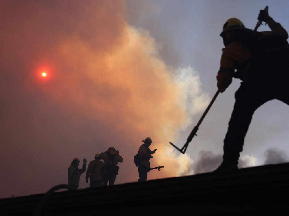 Firefighters work as a brush fire burns in Pacific Palisades, California.