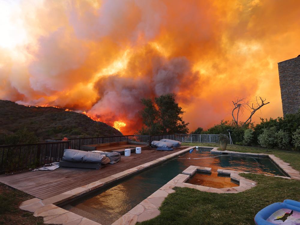 A fast-moving brushfire in a Los Angeles suburb burned buildings and sparked evacuations Tuesday as 