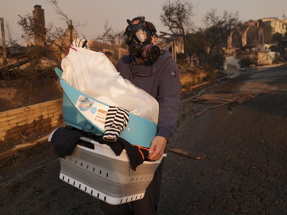 Thurs., Jan. 9: Josh Lederer wears a mask to protect him from fumes as he retrieves his children's clothes from his fire-raved property in the Pacific Palisades neighborhood.