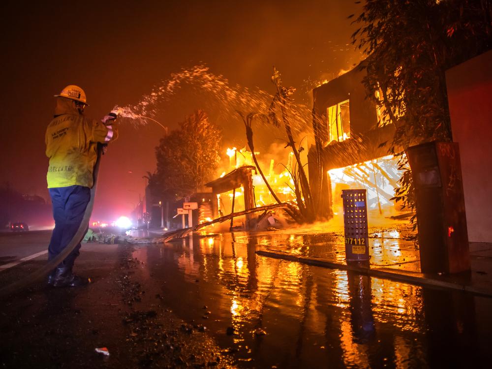 A firefighter battles the Palisades Fire, which is burning homes on the Pacific Coast Highway amid a powerful windstorm in Los Angeles on Wednesday.