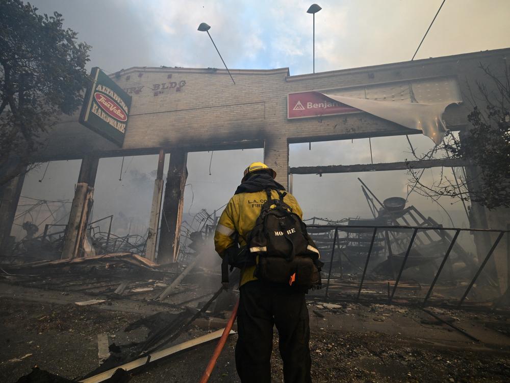 A firefighter extinguishes the remains of a hardware store destroyed in the Eaton fire in Altadena, California, on Wednesday.
