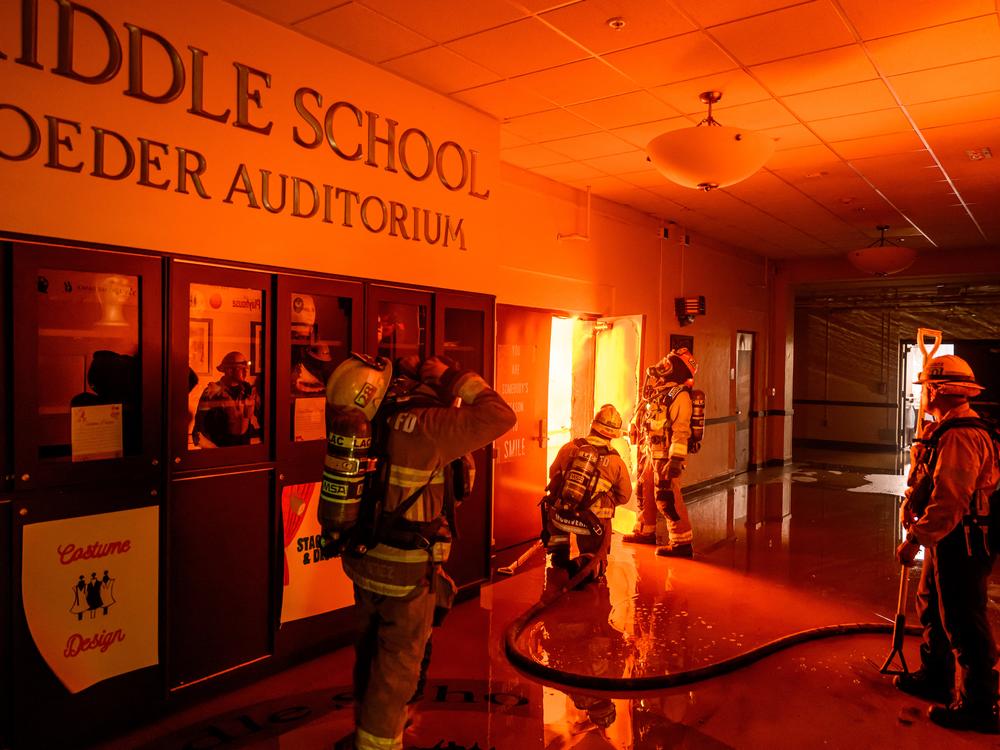 Wed., Jan. 8: Firefighters prepare to fight flames from inside Eliot Arts Magnet Middle School auditorium as the school burns during the Eaton fire in the Altadena area.