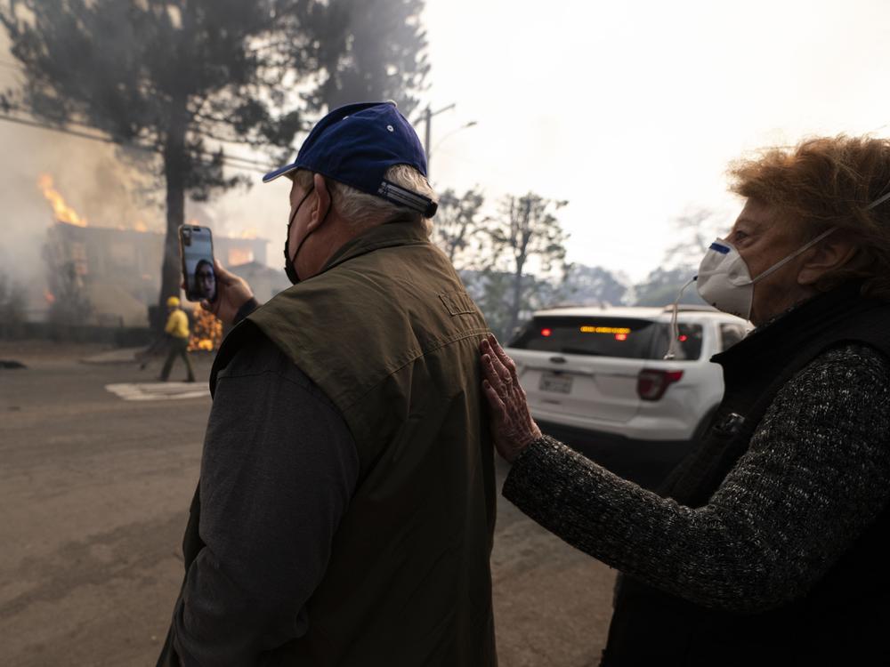 Altadena residents FaceTime a loved one as they watch their home burn in the Eaton Fire on Wednesday.