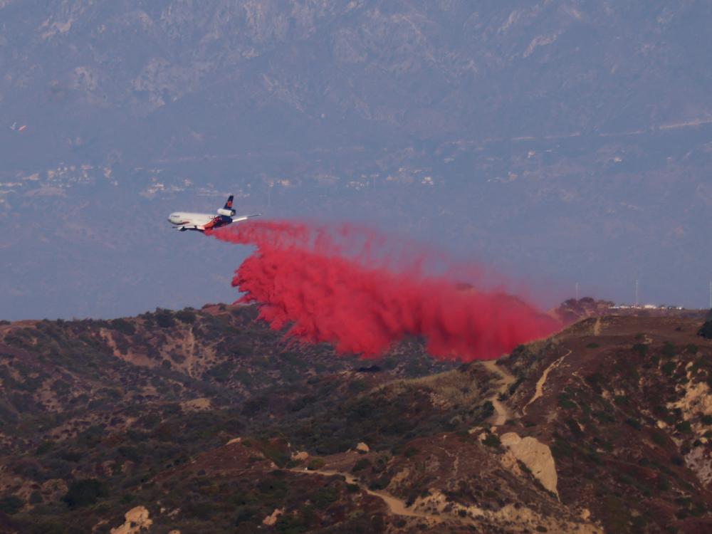 A tanker drops retardant as the Palisades Fire grows in the mountains in Topanga, Calif., on Thursday