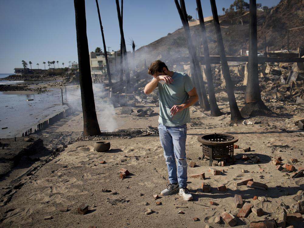 Friday, Jan. 10: Luke Dexter reacts as he sifts through the remains of his father's fire-ravaged beachfront property.