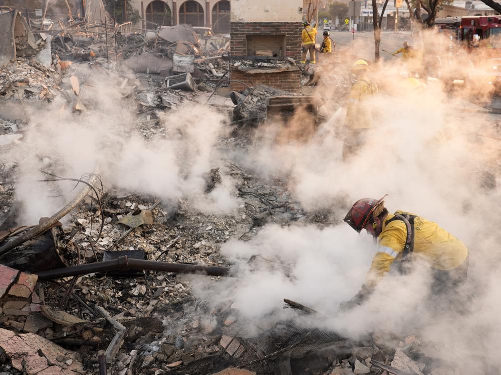 Friday, Jan. 10: A firefighter clears away smoking debris at the site of a structure on Lake Avenue in Altadena.