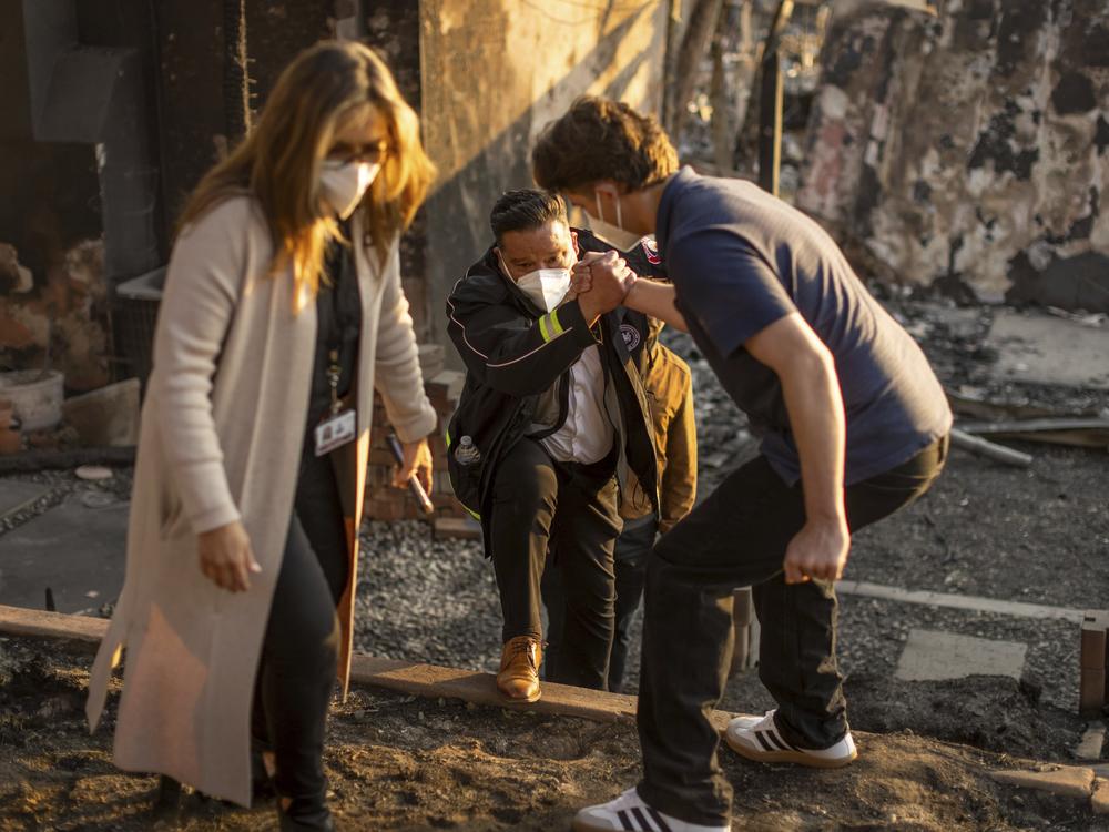 Friday, Jan. 10: A person helps up Pasadena Mayor Victor Gordo, center, as he meets with victims of the Eaton Fire.