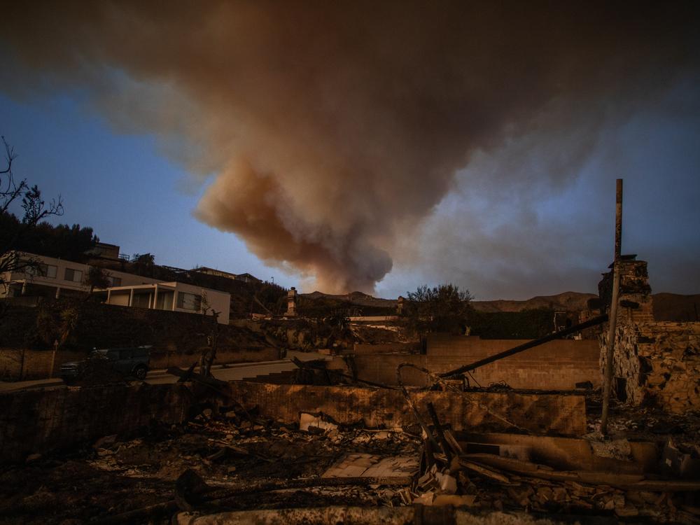 Friday, Jan.10: Wildfire smoke and burned houses are seen from the Palisades Fire in the Pacific Palisades neighborhood.