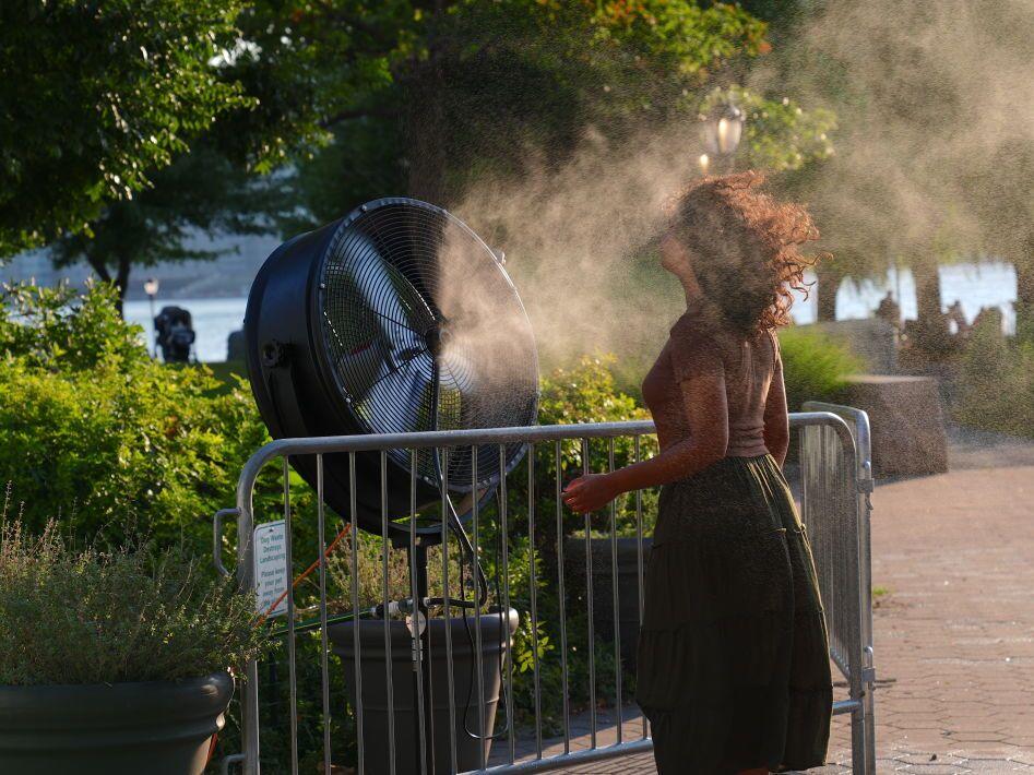 A woman cools off near a water-spraying fan during a New York City heat wave in July 2024. Heat broke records months in a row around the planet between 2023 and 2024.