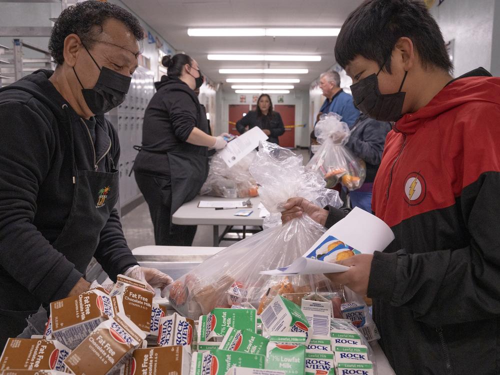 Jose Centeno hands food to LAUSD student Jesus Sanchez at Hollenbeck Middle School on Friday, Jan. 10.