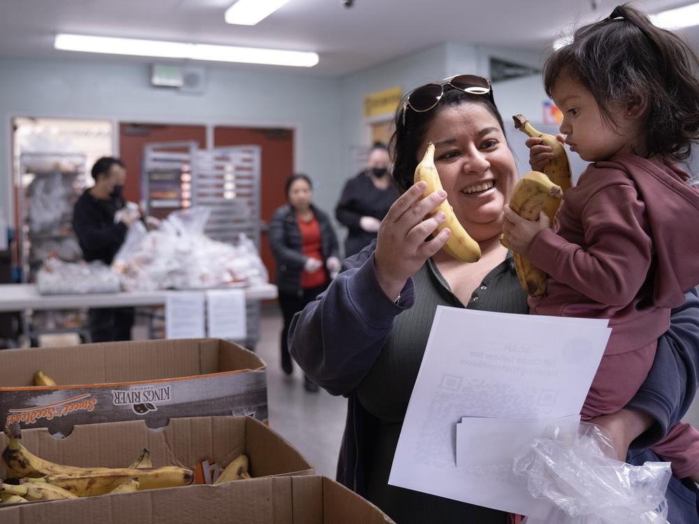 Rocio Manzo and her 1-year-old daughter, Jaliy, grab some bananas at Hollenbeck Middle School on Friday, Jan. 10. Hollenbeck has become a designated grab-and-go meal location for LAUSD students, along with 15 other sites across the district.