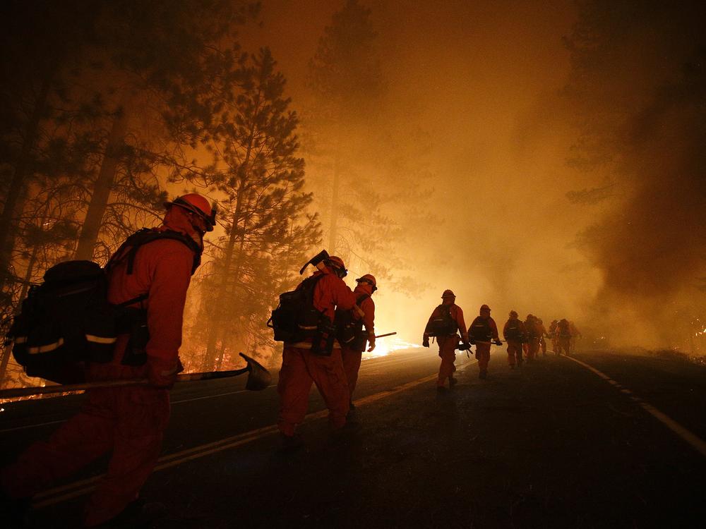 Inmate firefighters walk along Highway 120 during the Rim Fire near Yosemite National Park, Calif. in 2013. California currently has about 400 inmate firefighters battling the LA county wildfires.