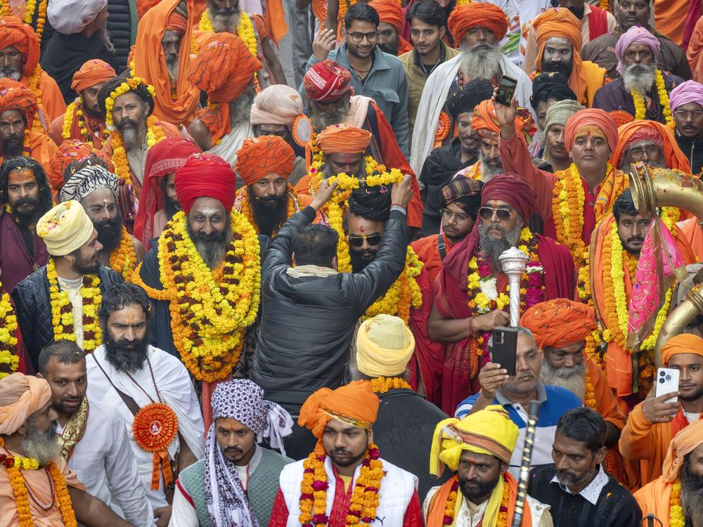 A devotee garlands a senior Hindu holy man walking in a procession, a day before the 45-day-long Maha Kumbh festival, in Prayagraj, India, on Sunday, Jan. 12, 2025.