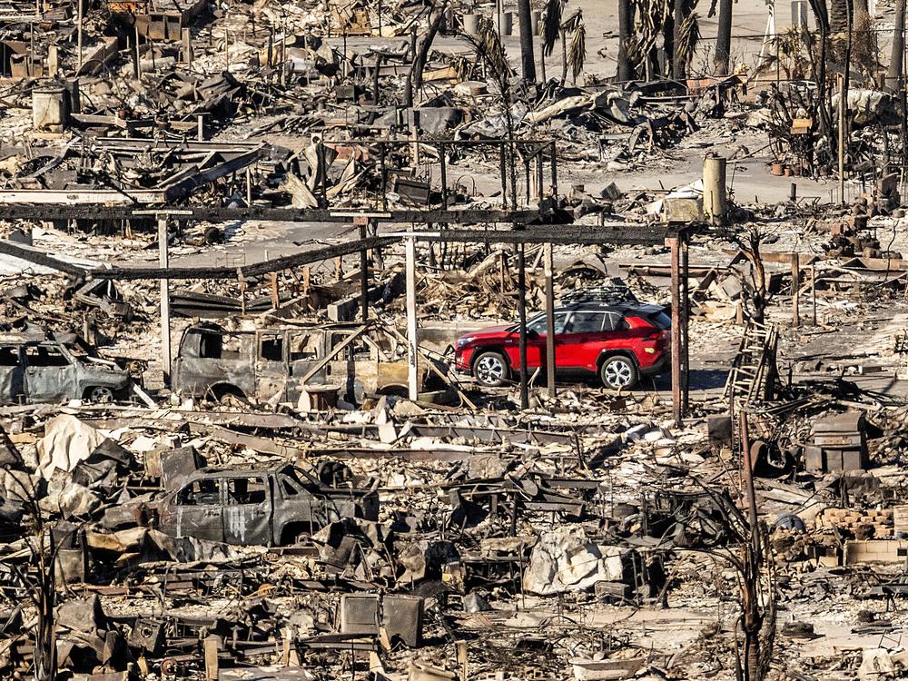 Sunday, Jan. 12: A car drives past homes and vehicles destroyed by the Palisades Fire at the Pacific Palisades Bowl Mobile Estates in Los Angeles.