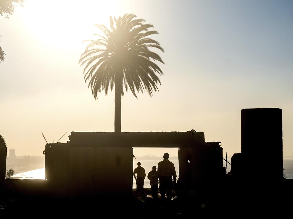 On Sunday, firefighters from an Oregon strike team survey damage at a Sunset Boulevard home leveled by the Palisades Fire in the Pacific Palisades community.