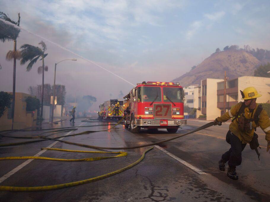 A firefighter drags a hose during the Palisades Fire on Jan. 8, 2025 in Malibu, Calif.