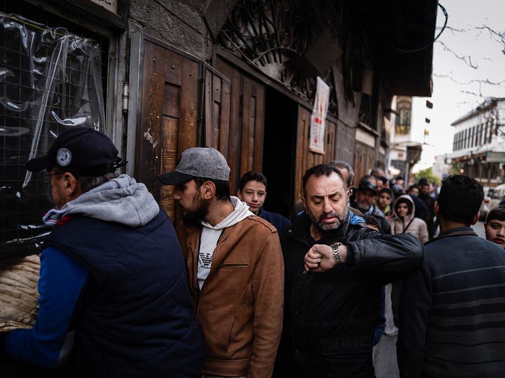 A Syrian man checks his watch while waiting at a breadline at a bakery in the Syrian capital Damascus.