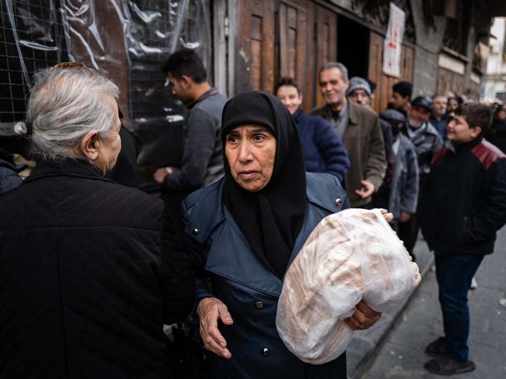 A woman collects her bread at a bakery in the Syrian capital Damascus. Bread costs up to ten times more than it did just weeks ago — from 400 Syrian lira to 4,000 Syrian lira for a dozen pieces of dinner-plate-size flat bread. That new price is the equivalent of 31 cents.<br>
