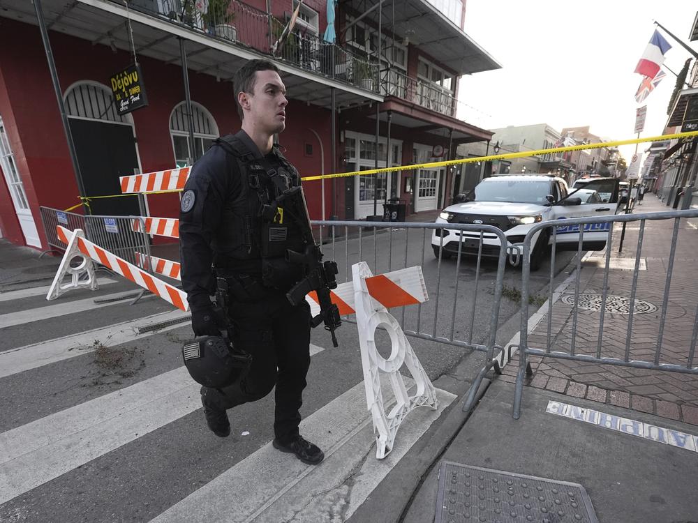 A member of the emergency services walks past a police barricade after a vehicle drove into a crowd on New Orleans' Canal and Bourbon Street.