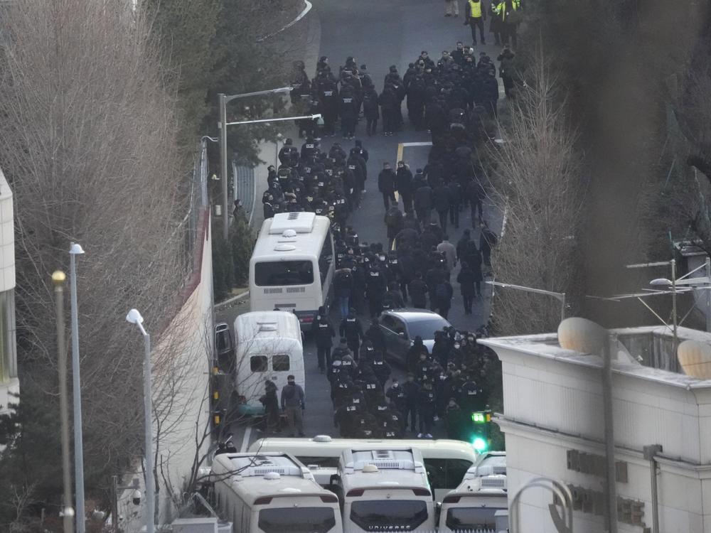Investigators from the state anti-corruption agency and police officers make their way to the residence of impeached President Yoon Suk Yeol to execute a warrant to detain Yoon in Seoul, South Korea, Wednesday, Jan. 15, 2025.