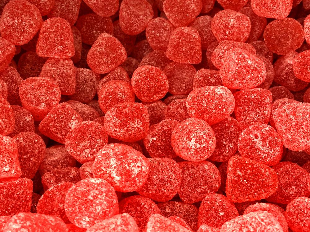 Stock photo of sweet shop pic and mix display of sugar coated red jelly sweet / gummy drops.