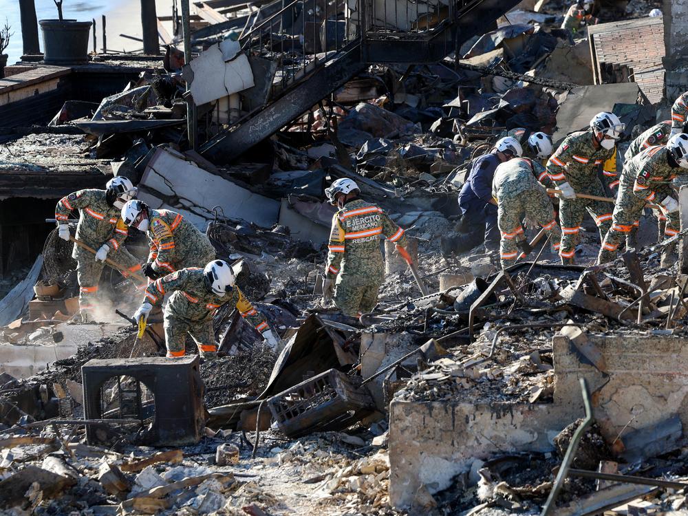 An urban search and rescue team from Mexico combs through the ruins of a beachfront house searching for victims in the aftermath of the Palisades Fire in Malibu, Calif., on Tuesday.