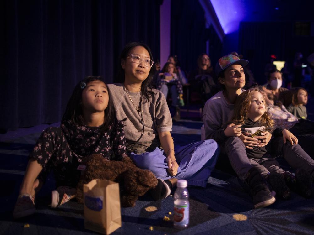 Iris Wong (left) sits with her mothe, Tina Yen, and Tania Verafield holds her son, Leo Bane, as they watch the show.