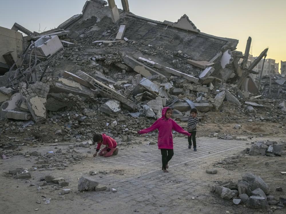 Palestinian children play next to a building destroyed by Israeli attack in the central Gaza Strip town of Khan Younis on Jan. 1.