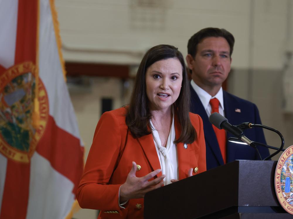 Florida Gov. Ron DeSantis listens as Florida Attorney General Ashley Moody speaks during a press conference on Sept. 17, 2024 in West Palm Beach, Fla.