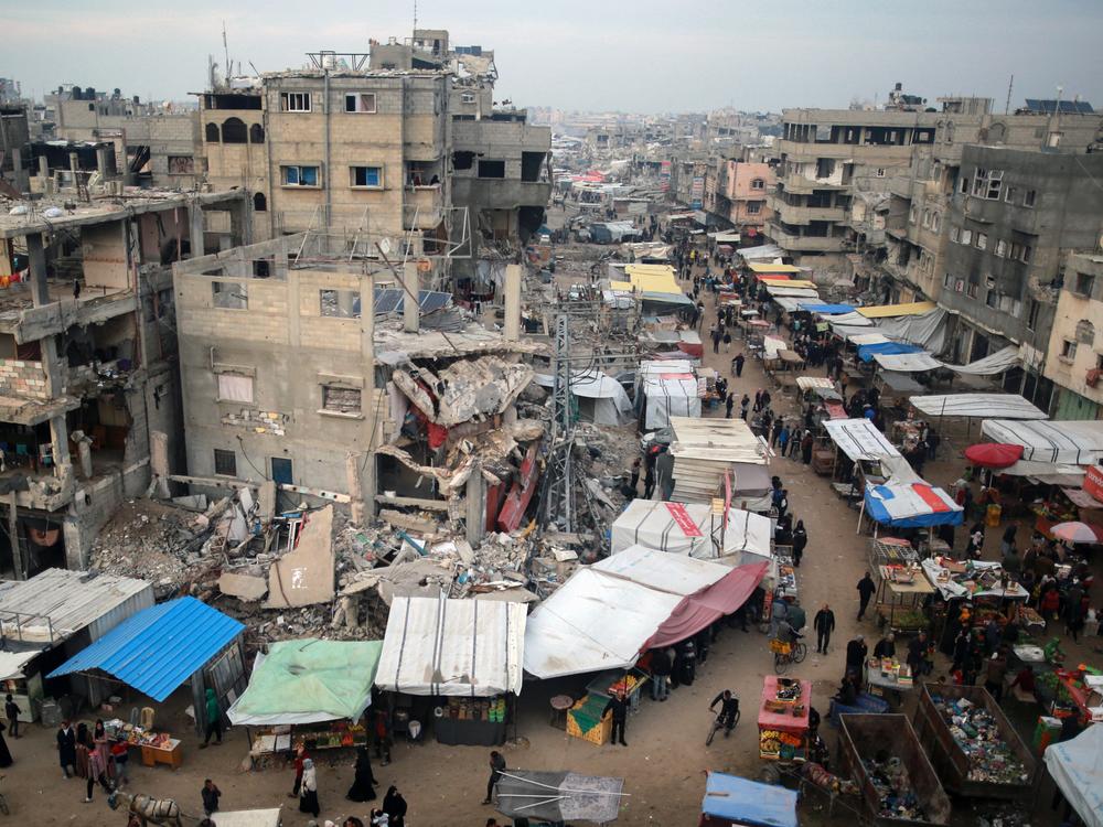 People walk past stalls selling goods amid the rubble of buildings destroyed in Israeli strikes, in Khan Younis in the southern Gaza Strip on Wednesday.
