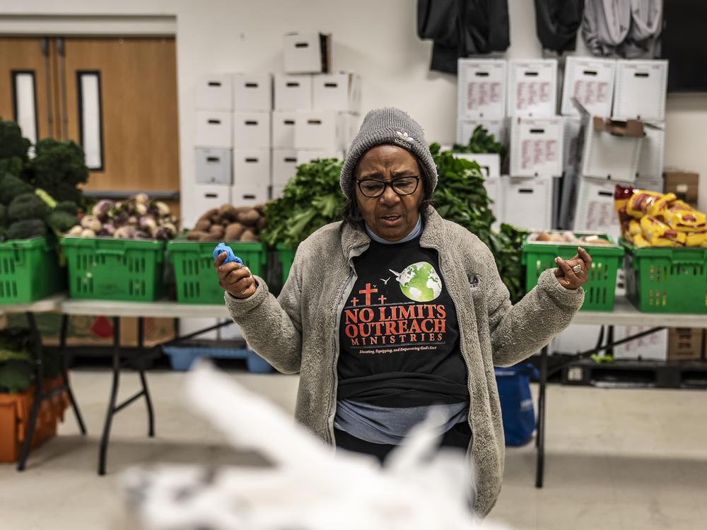 Pantry team member Gloria Jarmon leads volunteers in a prayer before the door is opened to let people in.