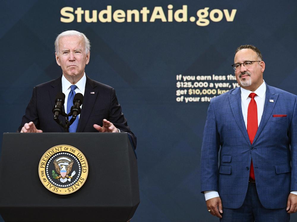 U.S. Education Secretary Miguel Cardona looks on in October 2022 as President Biden delivers remarks about the online portal for his first, big student debt relief effort – an effort that was ultimately struck down by the Supreme Court.