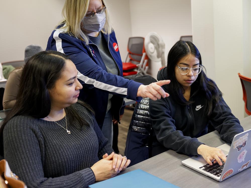 Ashton Spatz, center, a financial aid adviser with the University of Illinois at Chicago, assists Jessena Sanchez, left, and her daughter, Leslie Delve, a sophomore at UIC, during a FAFSA workshop in February 2024.