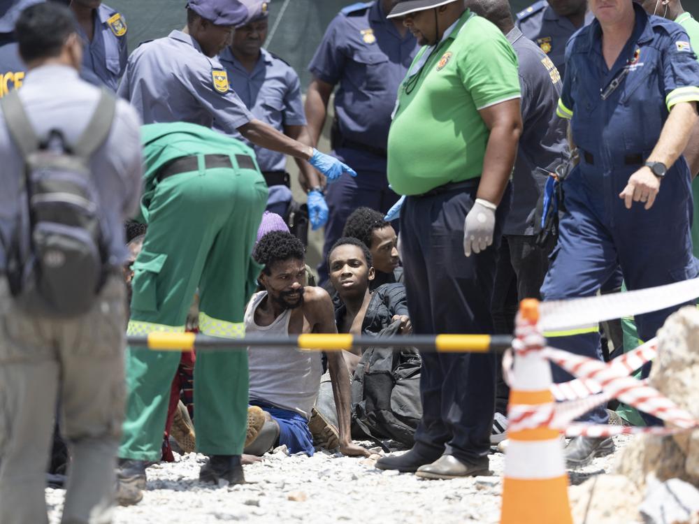 Illegal miners rescued from an abandoned gold mine sit on the floor as rescuers and South African Police Service (SAPS) officers record their details and provide assistance in Stilfontein on January 14, 2025.