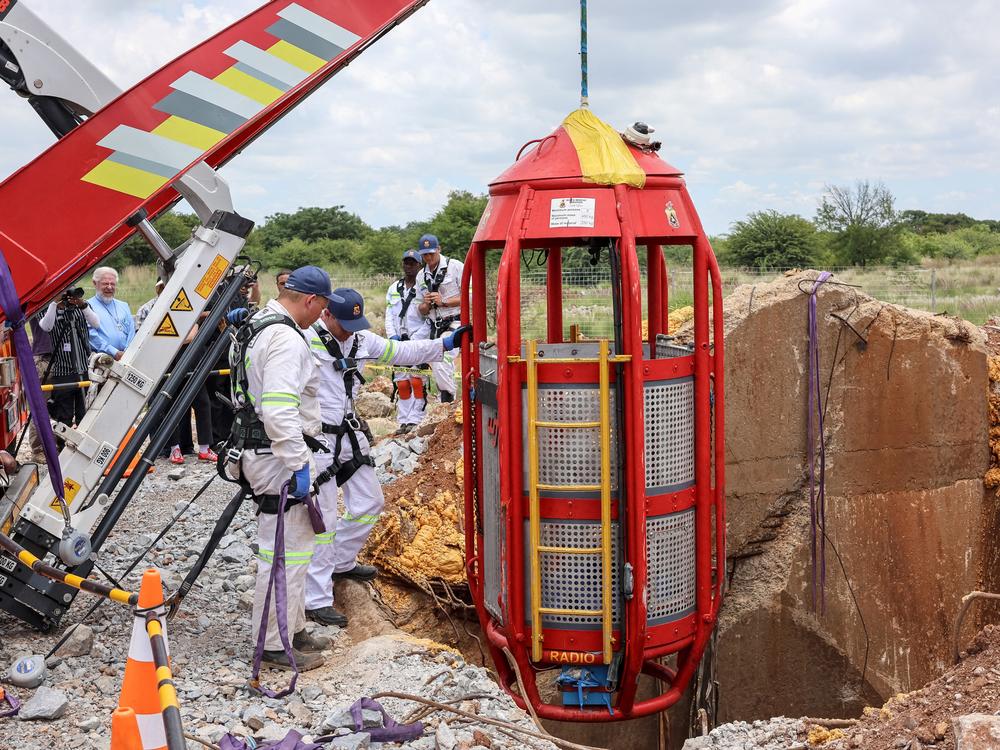Rescue workers look on as a cage is lifted from an abandoned gold shaft in Stilfontein on January 16, 2025.