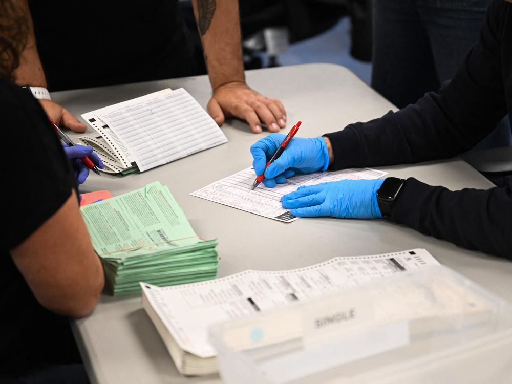 Pairs of election workers from different political parties open and inspect mail ballot envelopes inside the Maricopa County Tabulation and Election Center in Phoenix on Election Day, Nov. 5, 2024.