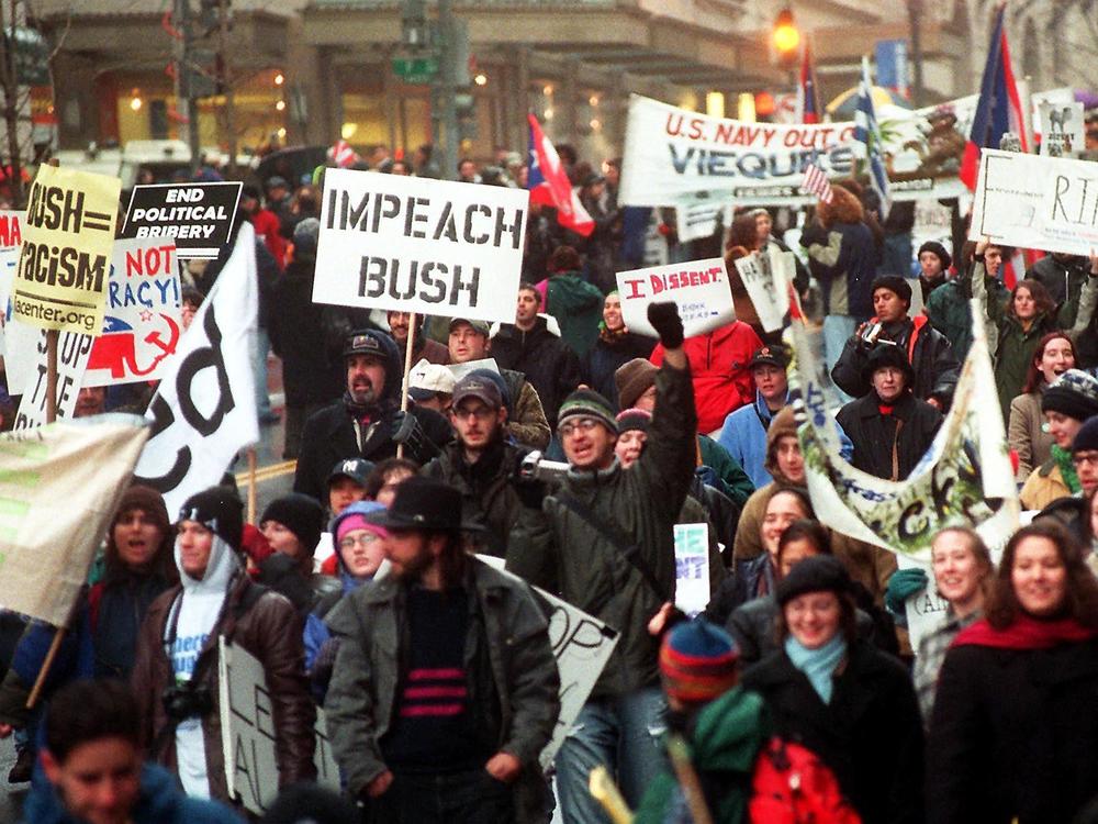 Hundreds of demonstrators wave signs and shout as they march through the streets of Washington, D.C., Jan. 20, 2001, in protest of the inauguration of U.S. President-elect George W. Bush.