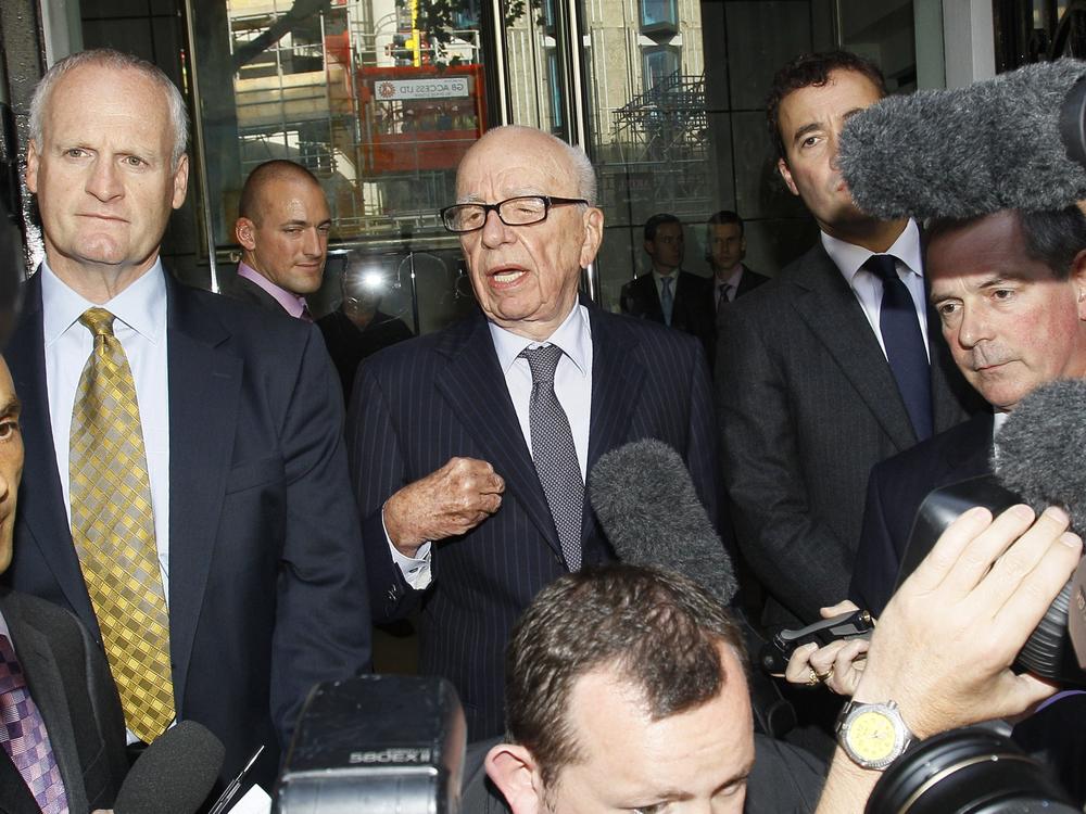 Rupert Murdoch, center, speaks to the media after meeting with the family of murdered school girl Milly Dowler in London on July 15, 2011. His tabloids hacked into Dowler's phone messages, outraging the nation. Will Lewis, now the CEO of <em>The Washington Post,</em> is on the right, partly obscured by a microphone.
